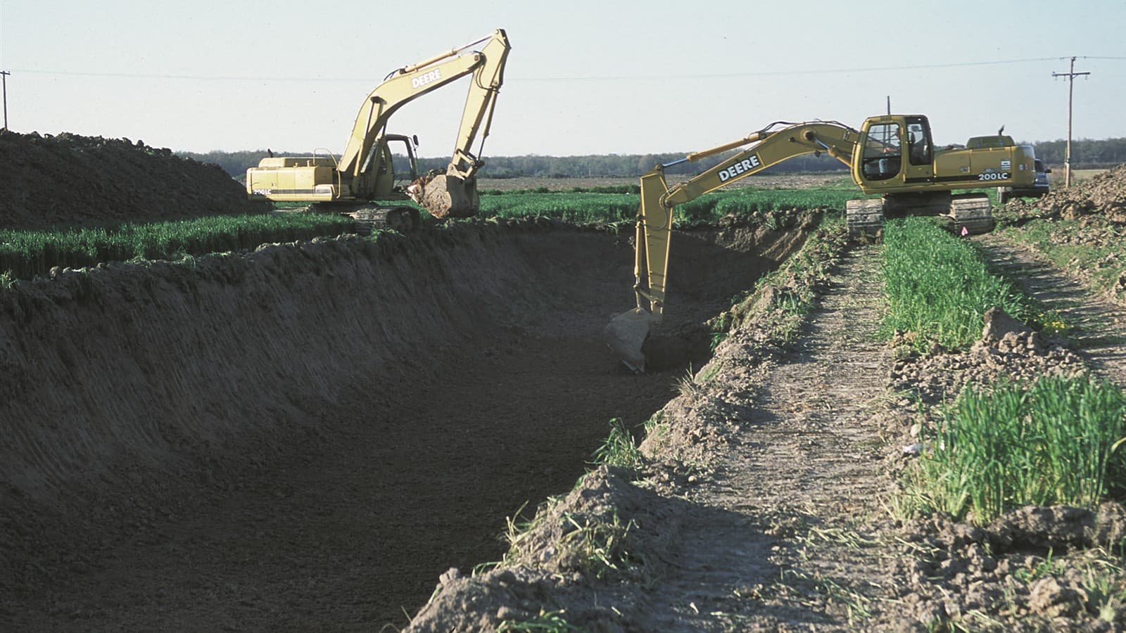 Two yellow excavators dig a tailwater recovery pond in a farm field in Lonoke County, Arkansas.