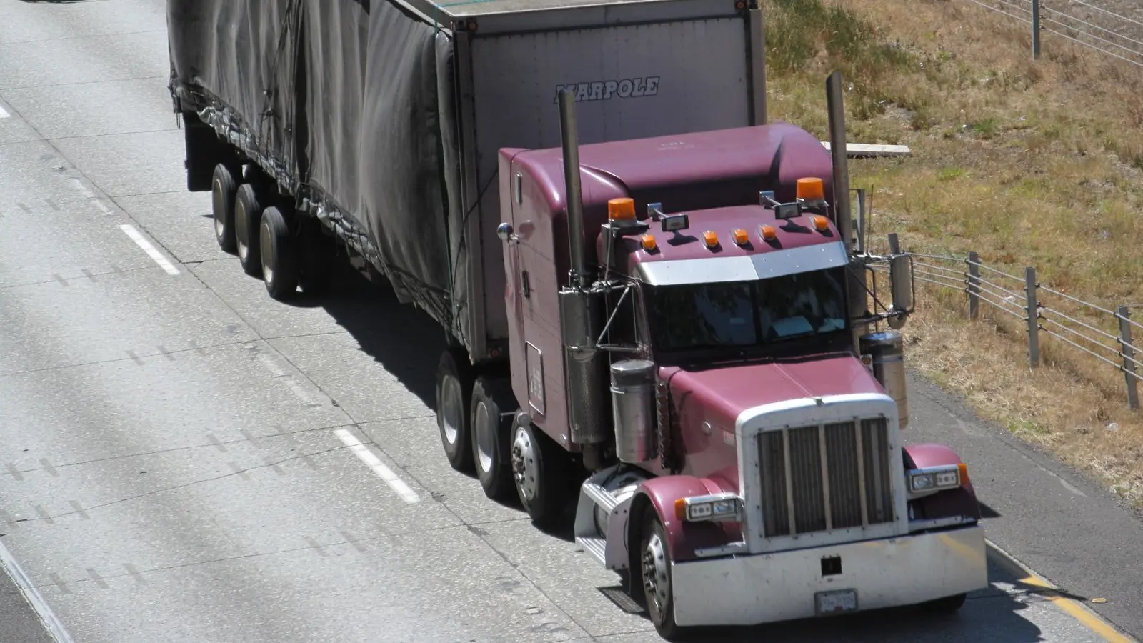 A maroon tractor pulls a tarp-covered semi-trailer along Interstate 5 near Bellingham, Washington.