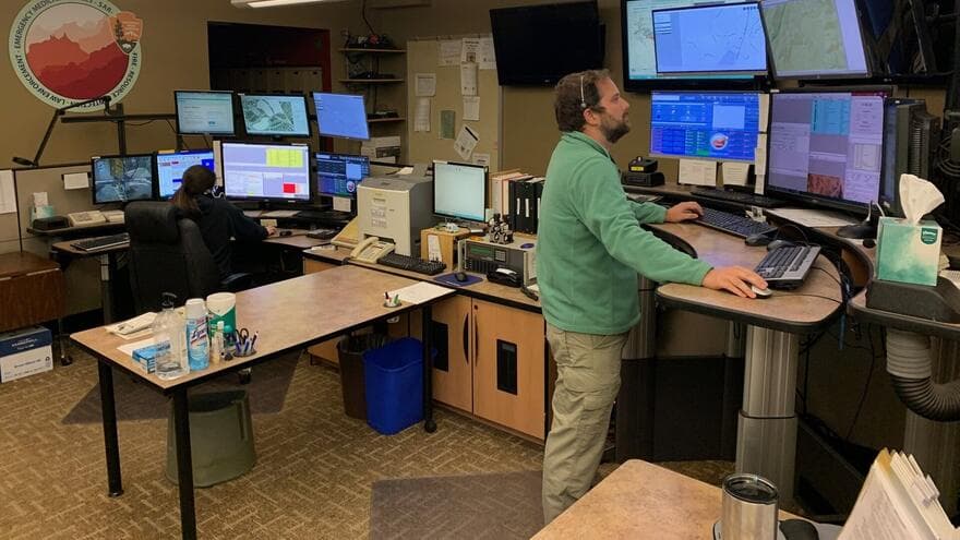 Two dispatchers work at desks lined with monitors and maps at a regional communications center in Arizona.